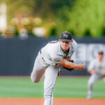 Baseball pitcher in gray uniform delivering a pitch on a mound, WF cap visible, field blurred in background