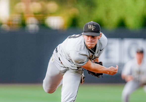 Baseball pitcher in gray uniform delivering a pitch on a mound, WF cap visible, field blurred in background