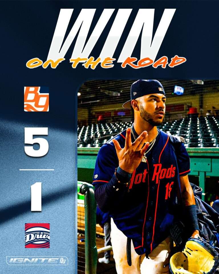 Baseball player in a blue jersey and cap walks out from the dugout on a promotional poster that reads 'WIN ON THE ROAD' at the top.