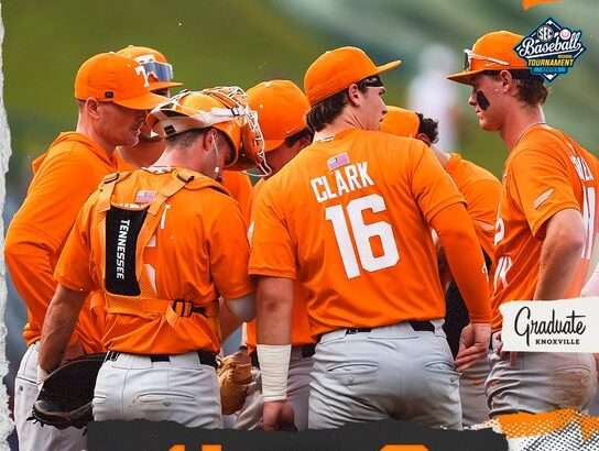 Group of college baseball players in orange uniforms huddle on the field; score shows 4-8 with team logos at bottom. The back of player Clark #16 is visible.