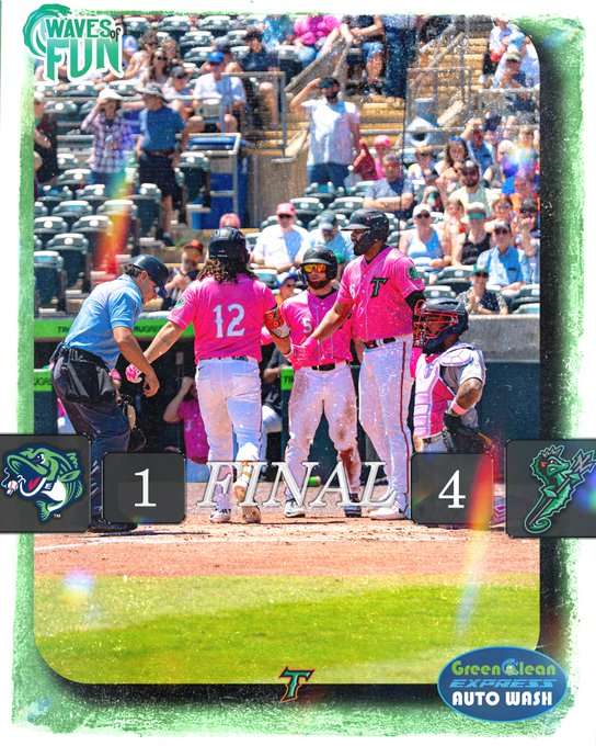 Baseball players in pink uniforms celebrate on the field after a 4–1 victory; final score displays 1–4 with team logos visible.