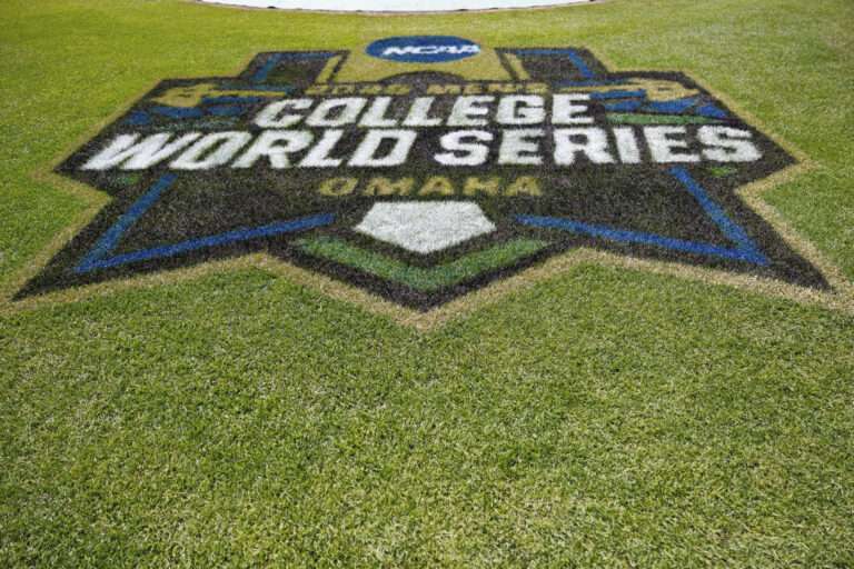 College World Series logo painted in turf on a baseball field, with green grass surrounding it.