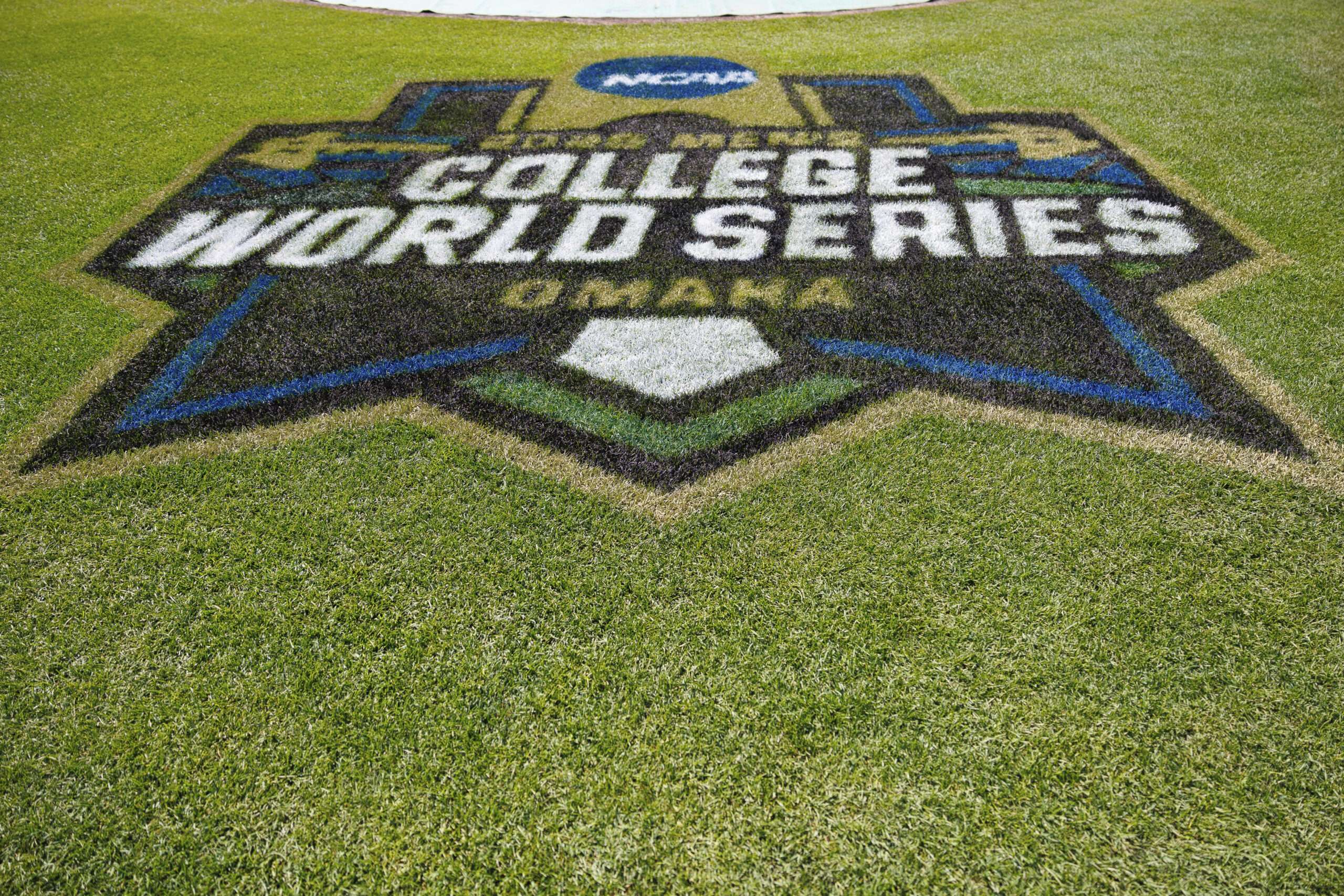 College World Series logo painted in turf on a baseball field, with green grass surrounding it.