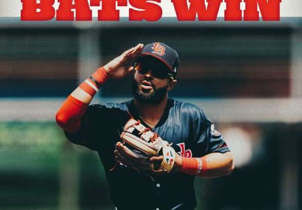 batsandstripers » Greenville Sports Media Baseball player in a blue uniform saluting with a large red 'BATS WIN' headline above him.
