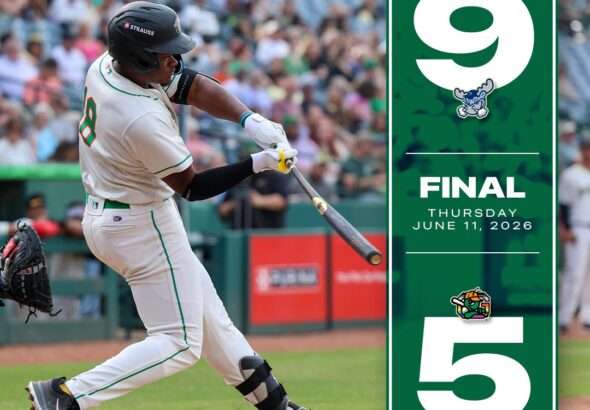 grasshoppers5 » Greenville Sports Media Batter in a white baseball uniform swings at a pitch in the batter's box with crowds in the stands; a tall green final banner stands to the right with a large 9 and 5 and the date June 11, 2026.