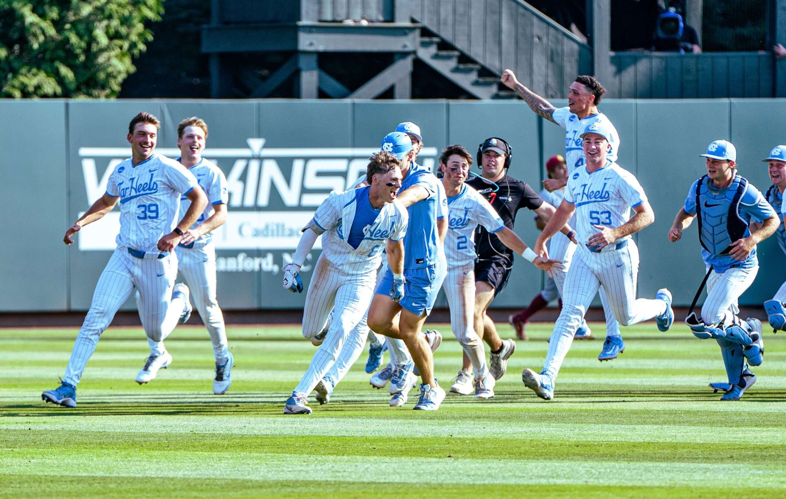 Baseball players in light-blue and white uniforms sprinting across the field in celebration.