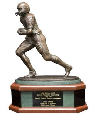 Bronze statue of a football player running, mounted on a wooden base with a plaque.